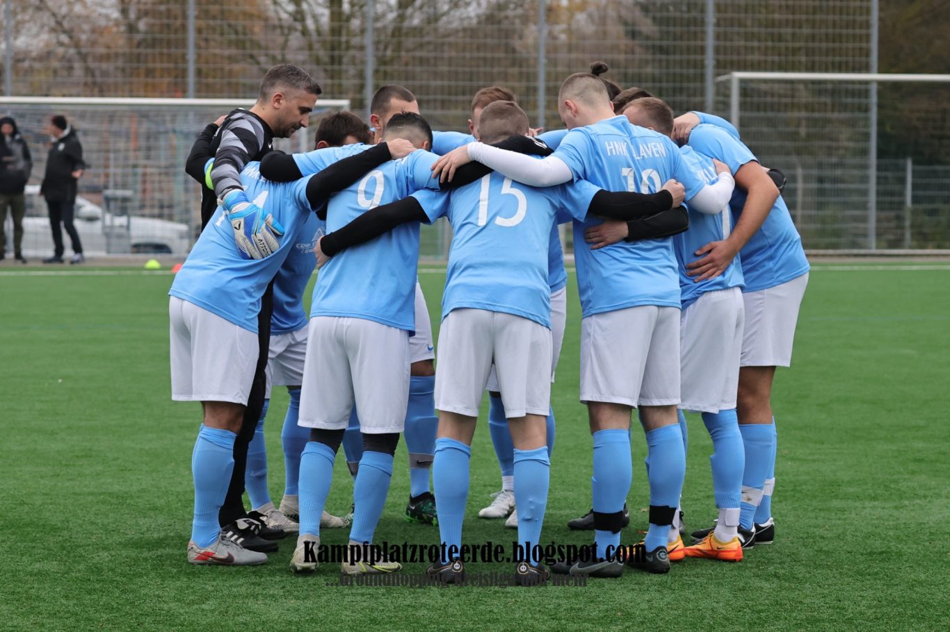 Mannschaft versammelt sich im Kreis zum Teamgespräch auf dem Fußballfeld.