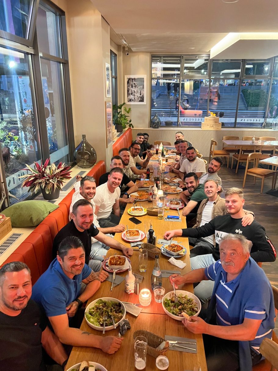 Große Gruppe von Menschen am Tisch, die gemeinsam essen und feiern.