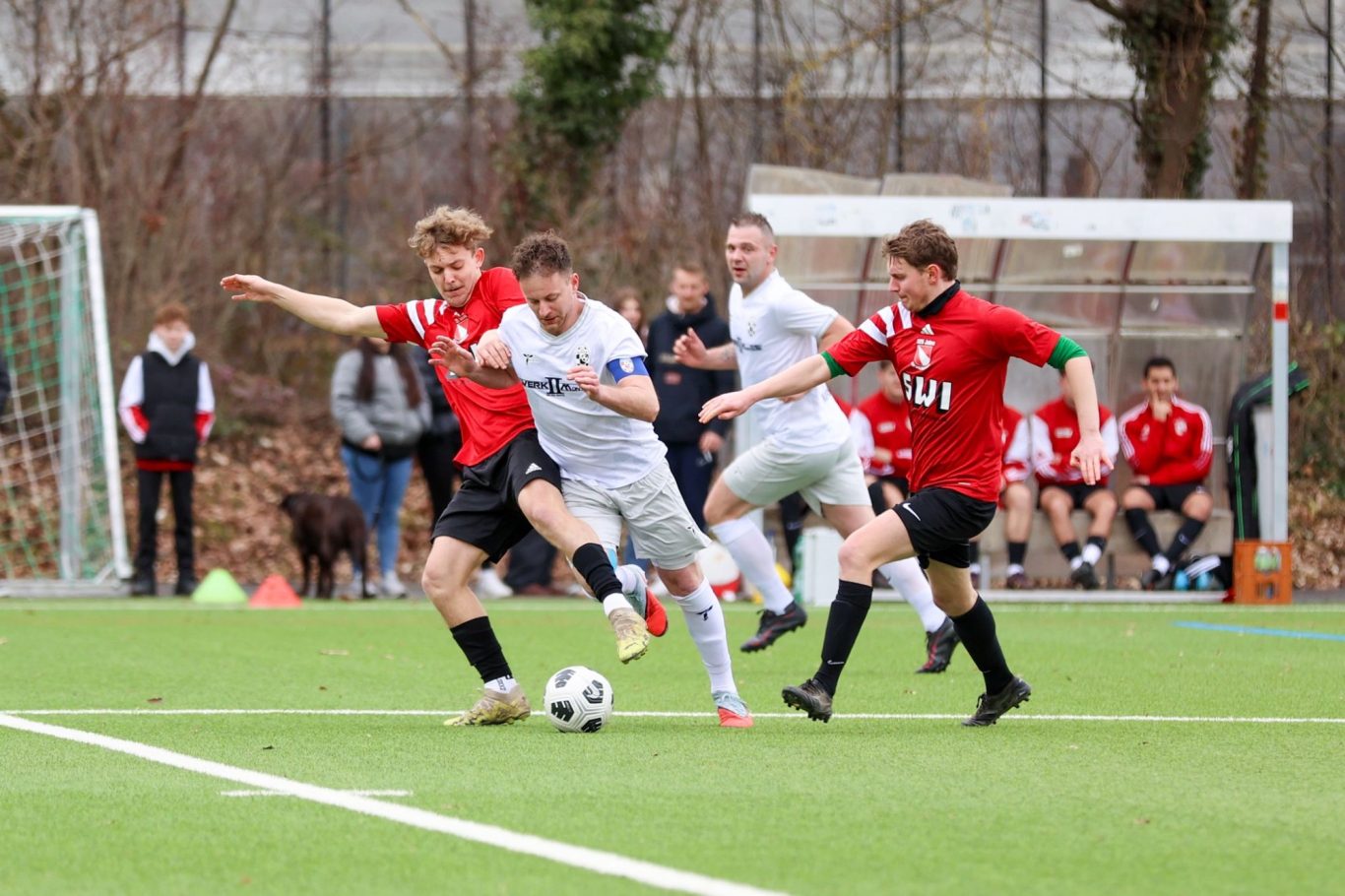 Zwei Fußballspieler im Wettkampf um den Ball auf einem Rasenplatz.